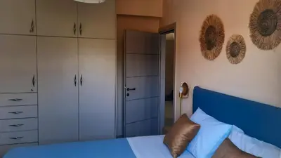 a bedroom with a blue bed and white cabinets at Elena Apartments in Kato Daratso