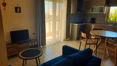 a living room with a couch and a table and a kitchen at Elena Apartments in Kato Daratso