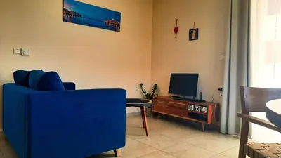 a living room with a blue chair and a tv at Elena Apartments in Kato Daratso