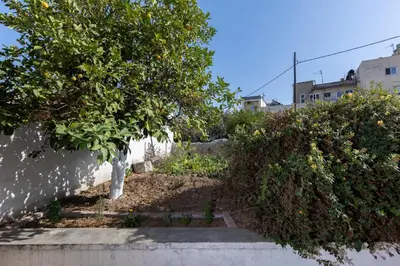 a garden with orange trees and bushes next to a wall at Argiro's House - Chania Old Town in Chania Town