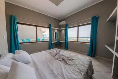 a bedroom with a bed with blue curtains and windows at Luxury Sea View Apartment in Kolimvari in Kolymvari