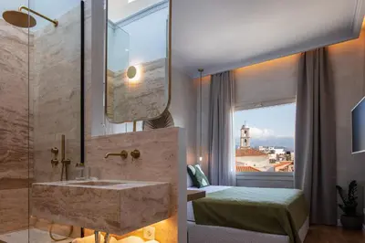 a bathroom with a sink and a bed and a window at La Torre Residenza Imperiale in Chania Town