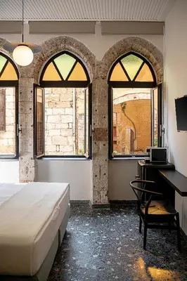 a bedroom with a bed and a desk and windows at Faedra Residence in Chania Town