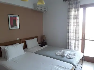 two twin beds in a bedroom with a window at kera apartments in Kalyves