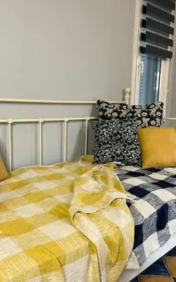 a bed with a yellow and white blanket on it at Pink House 2 in Palaiochóra