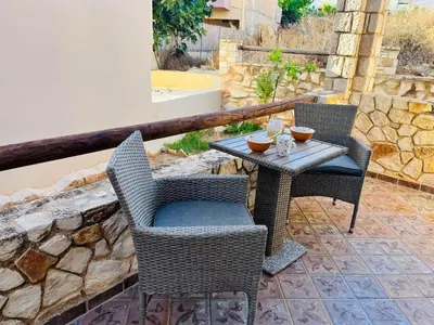 two wicker chairs and a table on a patio at Pink House 2 in Palaiochóra