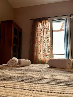 a bedroom with two beds with towels and a window at Pink House 2 in Palaiochóra