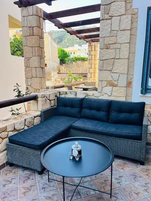 a blue couch and a glass table on a patio at Pink House 2 in Palaiochóra