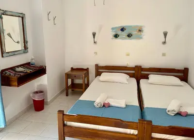 two twin beds in a room with a mirror at BONATSA ROOMS in Palaiochóra
