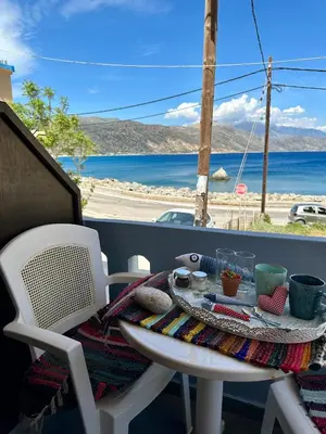 a table and chairs on a balcony with a view of the ocean at BONATSA ROOMS in Palaiochóra