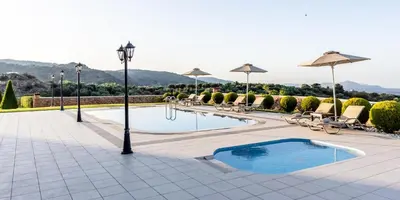 a pool with chairs and umbrellas on a patio at Ktima Edem in Ramní