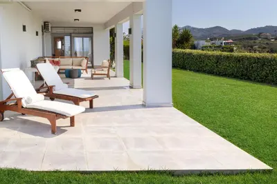 a patio with two chairs and a lawn at Villa Pasiphae in Stalos