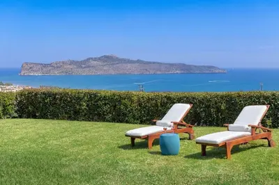 two lounge chairs sitting in the grass near the ocean at Villa Pasiphae in Stalos