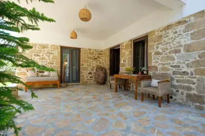 a patio with a stone wall and a table and chairs at Apartments Panethimos in Panéthimos