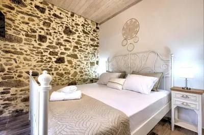 a bedroom with a bed and a stone wall at Apartments Panethimos in Panéthimos