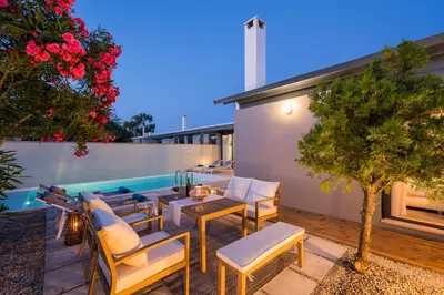 a patio with a table and chairs next to a pool at Natura Hill Villa III Sunset View in Kounoupidhianá