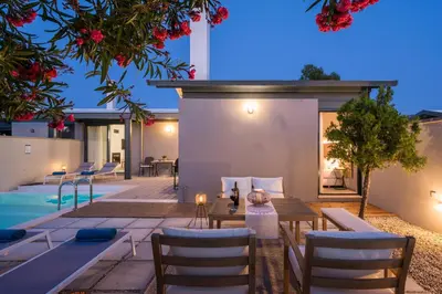 a patio with a table and chairs next to a pool at Natura Hill Villa III Sunset View in Kounoupidhianá