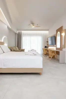 a white bedroom with a bed and a desk at Epavli Grace Hotel in Chania Town