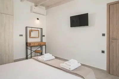 a bedroom with a bed and a tv on the wall at Megalith Villas in Agia Marina Nea Kydonias