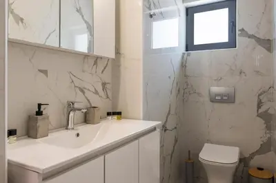 a white bathroom with a sink and a toilet at Megalith Villas in Agia Marina Nea Kydonias