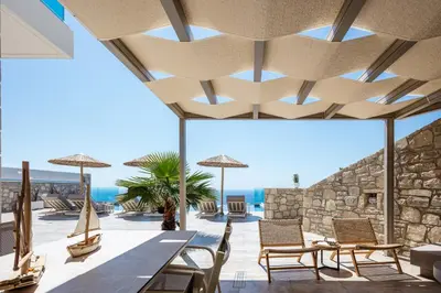 a patio with chairs and umbrellas and the ocean at Flower Village in Chania Town