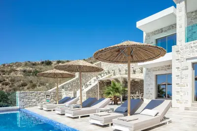 a group of chairs and umbrellas next to a pool at Flower Village in Chania Town