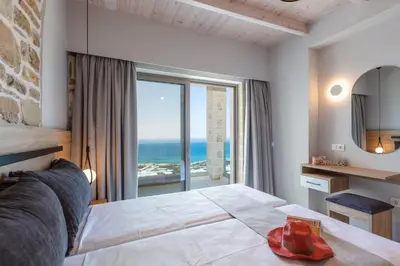 a bedroom with a bed with a view of the ocean at Flower Village in Chania Town
