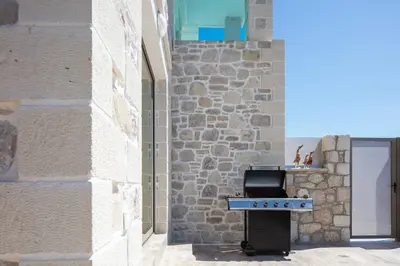a kitchen with a stove and a stone wall at Flower Village in Chania Town
