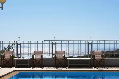 a fence with chairs and a swimming pool at Chrysiida Suites in Tersanas