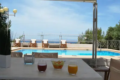 a table with two glasses of wine and a pool at Chrysiida Suites in Tersanas