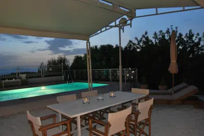 a patio with a table and chairs and a pool at Chrysiida Suites in Tersanas