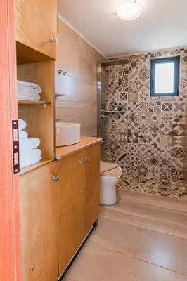 a bathroom with a toilet and a television on a wall at The Rock *Peaceful Retreat House in Kámbos