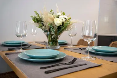 a table with plates and glasses and a vase of flowers at Inner City Retreat Apartment in Chania Town