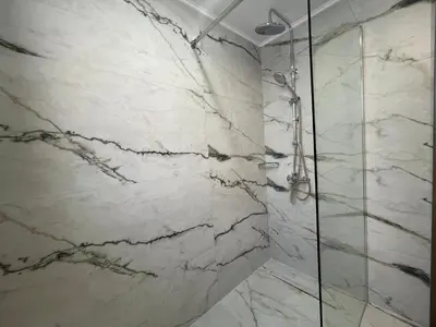 a bathroom with a shower with white marble walls at SK Luxury Residence in Chania Town