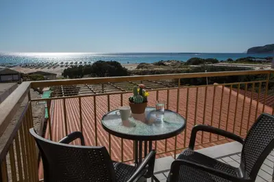 a table and chairs on a balcony with a view of the beach at En Plo Beachfront Rooms in Falasarna