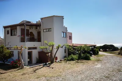 a white house on the side of a road at En Plo Beachfront Rooms in Falasarna