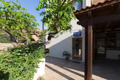 a sign in front of a building with a tree at En Plo Beachfront Rooms in Falasarna