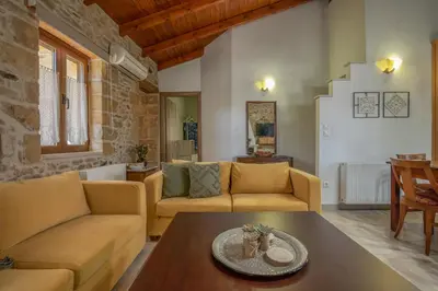 a living room with two couches and a table at Anthea Cottage in Kaloudhianá