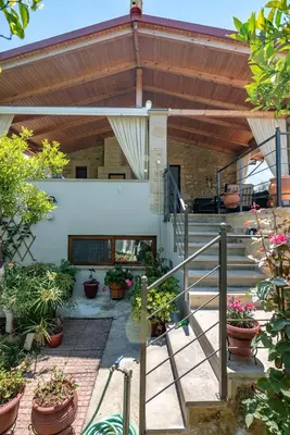 a house with a patio with plants and stairs at Anthea Cottage in Kaloudhianá