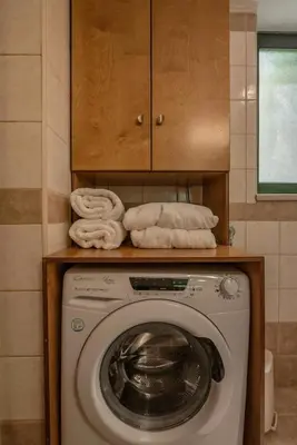 a washing machine in a bathroom with towels on a shelf at Anthea Cottage in Kaloudhianá