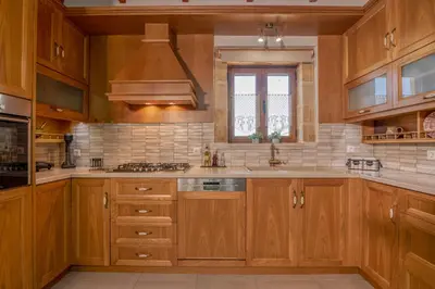 a large kitchen with wooden cabinets and a window at Anthea Cottage in Kaloudhianá