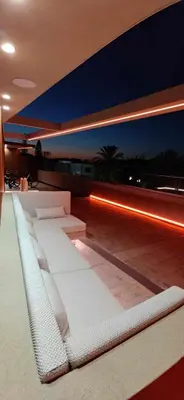 a room with white furniture on a roof at night at Summertime Signature Suites in Agia Marina Nea Kydonias