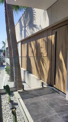 a building with a fence and a palm tree at Summertime Signature Suites in Agia Marina Nea Kydonias