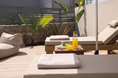 a patio with two chairs and two glasses of orange juice at Villa Methexis in Arménoi