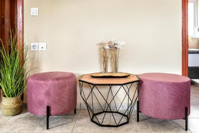 a table with two purple stools and a vase of flowers at House On The Beach In Kera - BY APOKORONAS VILLAS in Kalyves