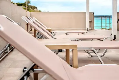 a row of chairs and tables on a balcony with the ocean at House On The Beach In Kera - BY APOKORONAS VILLAS in Kalyves