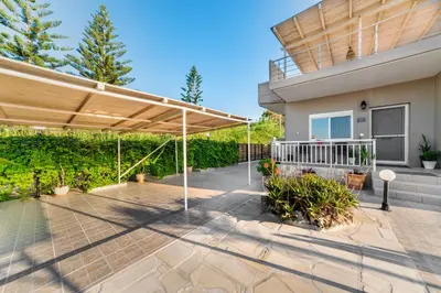 a patio with a wooden canopy in front of a house at House On The Beach In Kera - BY APOKORONAS VILLAS in Kalyves