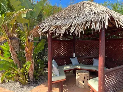 a wooden gazebo with a bench and a straw umbrella at Staffed, unique and luxurious coastal villa in beautiful Anidri, Paleochora in Palaiochóra