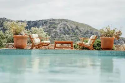 a group of chairs sitting next to a swimming pool at Staffed, unique and luxurious coastal villa in beautiful Anidri, Paleochora in Palaiochóra