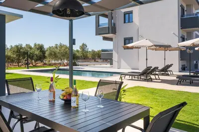 a wooden table with wine glasses on a patio at Aspect Luxury Apartments with Pool in Galangádhos